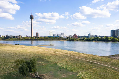 View of river and buildings against cloudy sky