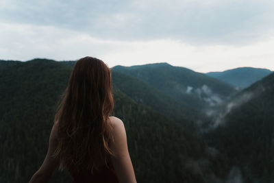 Rear view of woman standing on mountain against sky