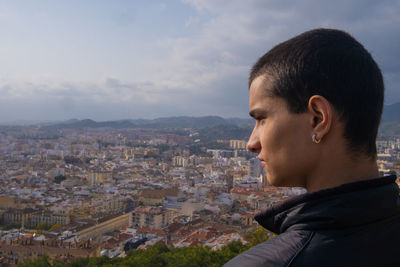 Portrait of young woman looking at city against sky