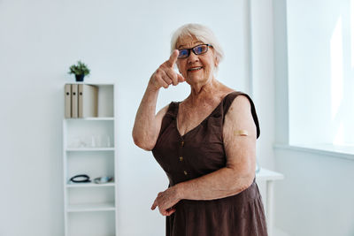 Portrait of senior woman gesturing while standing at hospital