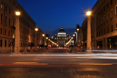 Light trails on city street by buildings at night