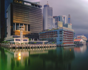 Reflection of buildings in lake against sky in city