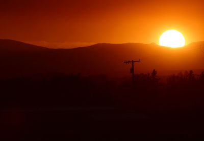 Scenic view of silhouette mountains against orange sky