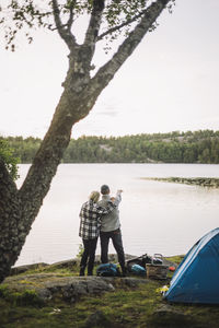 Woman standing with man looking at view from lakeshore