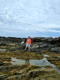 Man standing on rock against sky