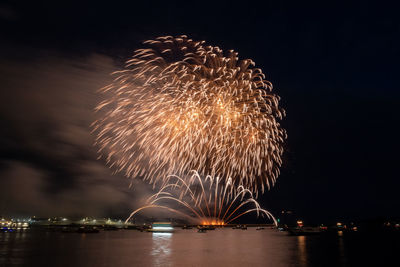 Firework display over river against sky at night