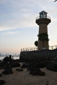 Lighthouse by sea against sky