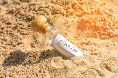 Close-up of paper in bottle on sand at beach