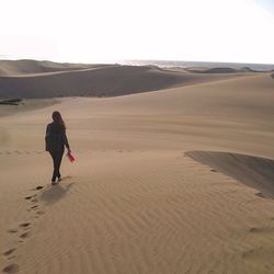 Rear view of man walking on sand dune