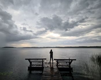Rear view of man standing on pier against sky