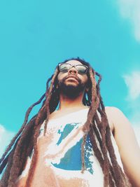 Low angle view of man with dreadlocks against blue sky