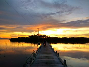 Pier over lake against sky during sunset