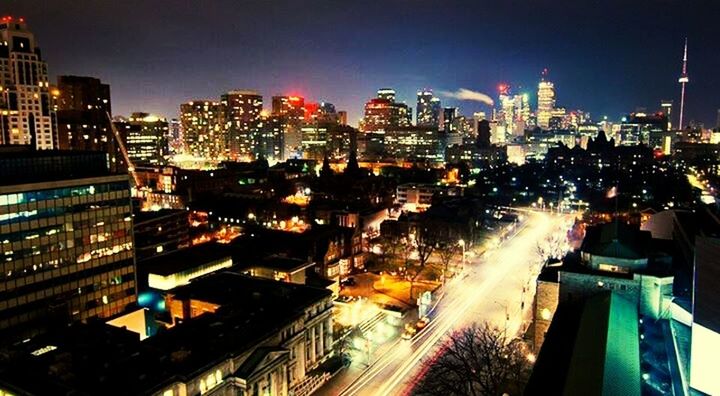 city, illuminated, building exterior, architecture, night, built structure, cityscape, skyscraper, transportation, high angle view, city life, light trail, road, modern, traffic, office building, tall - high, tower, long exposure, car