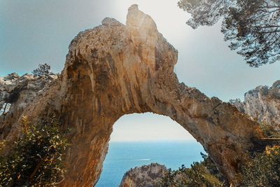 Rock formations by sea against clear sky