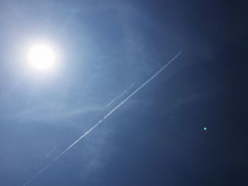 Low angle view of sun shining through clouds