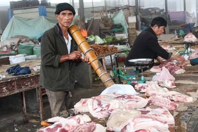 Portrait of butcher selling meat at market