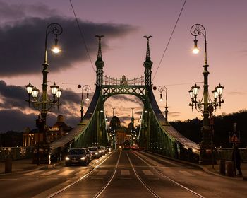 Liberty bridge against sky in city at dusk