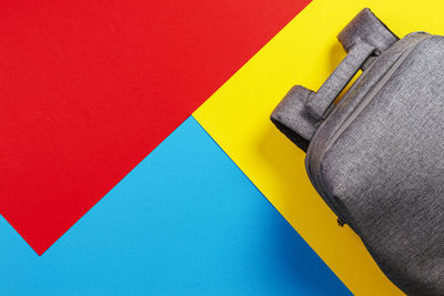 Top view of gray backpack on yellow, blue and red background.