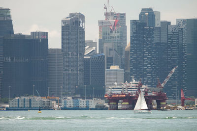 Sea by modern buildings against sky in city