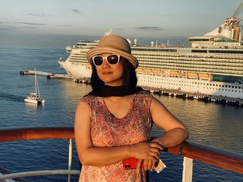 Young woman wearing sunglasses standing by sea against sky