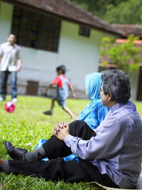 Happy couple sitting on grass in back yard