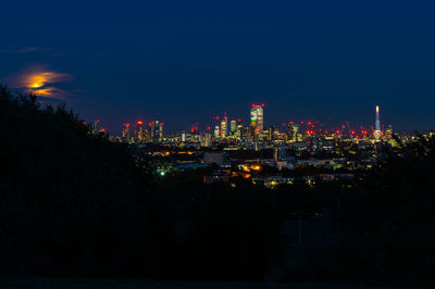 Illuminated cityscape against sky at night