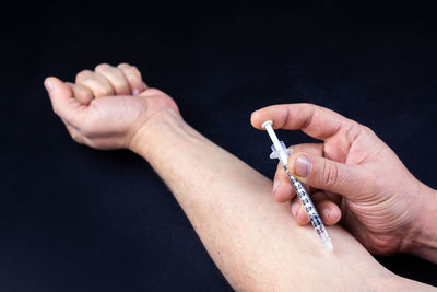 Close-up of hand holding hands over black background