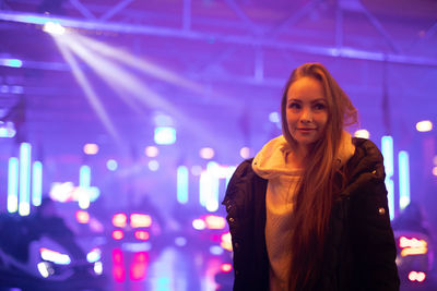 Portrait of smiling woman standing against illuminated light at night