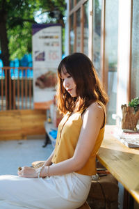 Side view of young woman sitting outdoors