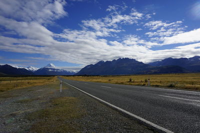 Road by mountains against sky