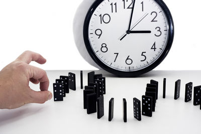 Close-up of hand holding clock over white background