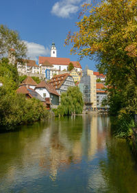 Buildings by river against sky