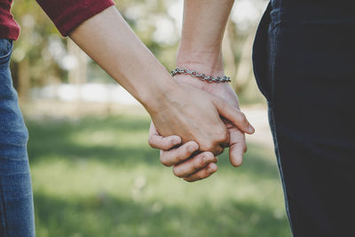 Midsection of couple holding hands