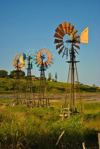 American-style windmills on field against clear sky