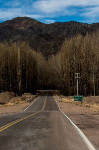 Empty road amidst trees against sky