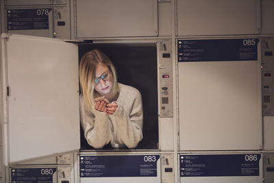 Young woman using phone in locker