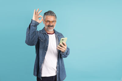 Young man using mobile phone against blue background