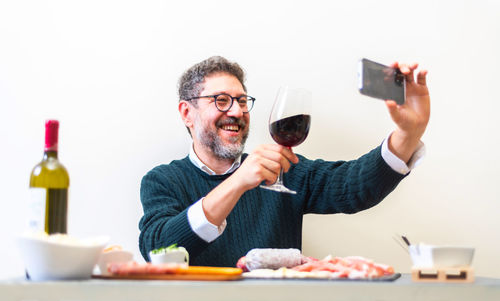 Man toasts in video call with a glass of wine and appetizer. adult men are making a pre-meal aperiti