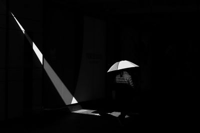 Woman standing against illuminated wall in dark room