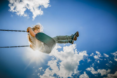 Girl on a swing reaching the clouds on a hot summer afternoon