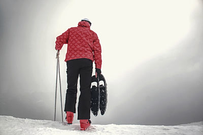 Man with snowshoes in the mountains in winter. man holding sticks walks through snow. winter ascent