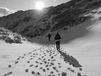 Rear view of people walking on snow covered field