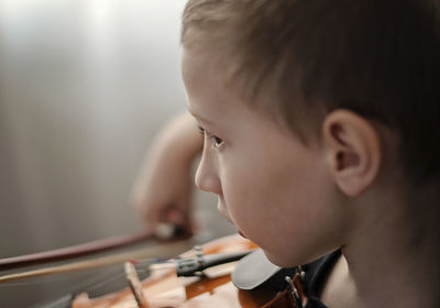 Close-up of boy playing violin at home