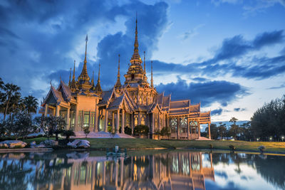 Temple by lake against sky during dusk