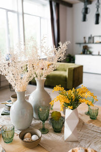 Festive easter table with mimosa flowers in a vase and traditional food, eggs. 