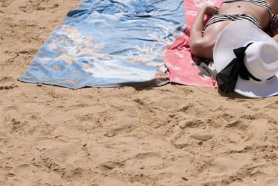 High angle view of woman sunbathing while lying on blanket at beach