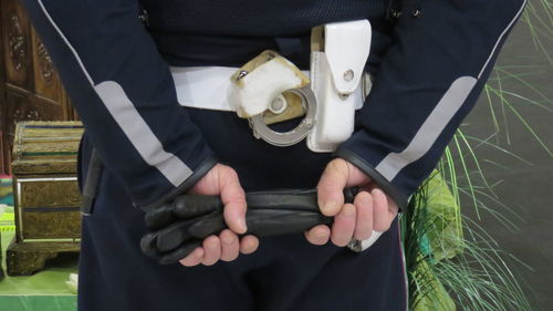 Midsection of male police officer holding protective glove