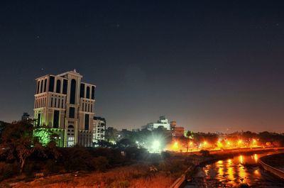 Illuminated city against clear sky at night