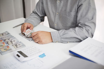 Midsection of man holding paper while sitting on table