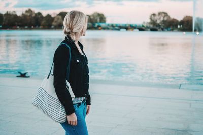 Rear view of woman standing by lake